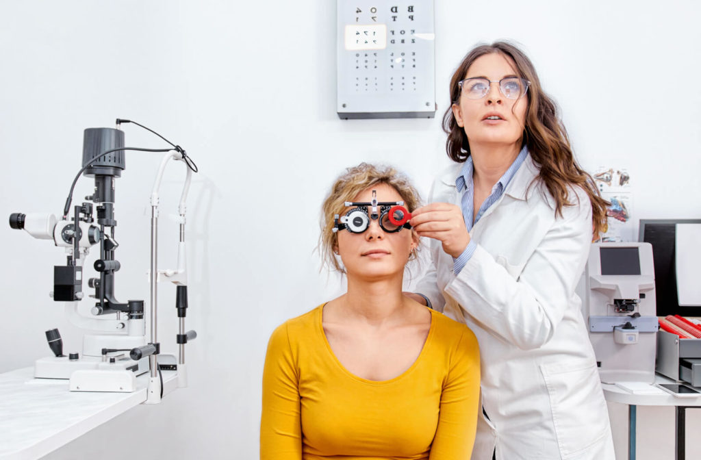 A female adult is undergoing an acuity test at the ophthalmology clinic and wearing a test eyeglass while her ophthalmologist is changing the lens of a test eyeglass.