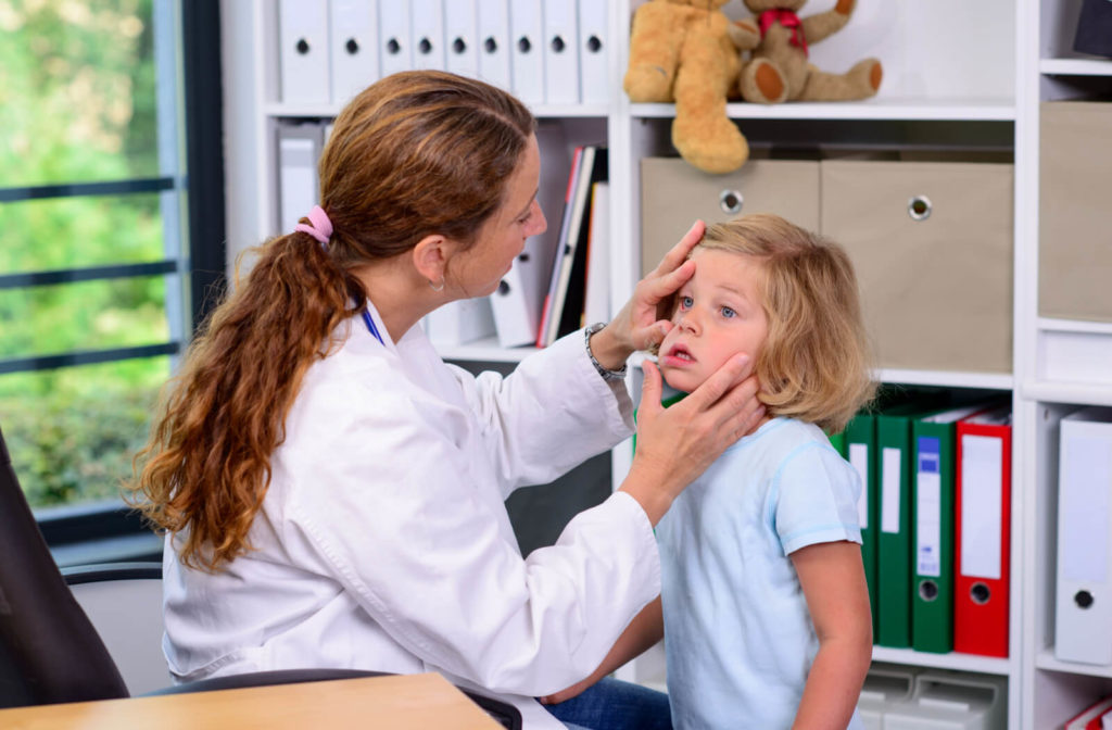 A female eye doctor is examining the eye of a young child.