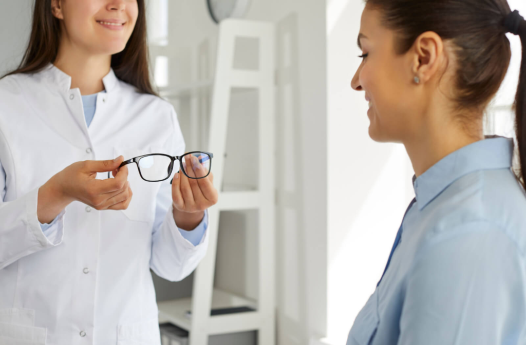 An optometrist giving a patient a pair of glasses for her to try on.