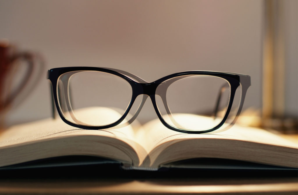 A point of view of a person suffering from double vision looking at a pair of eyeglasses on top of an opened book.