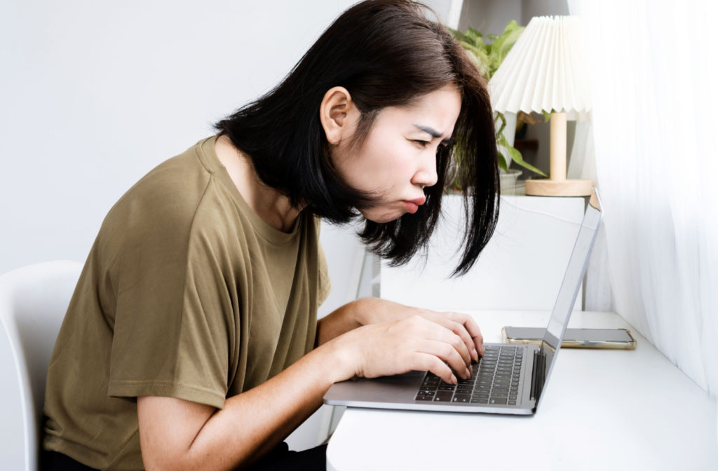A woman leaning closer to her laptop to see its contents better.