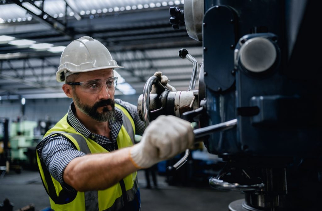 A mechanical engineer wearing safety glasses while he works on a piece of machinery.