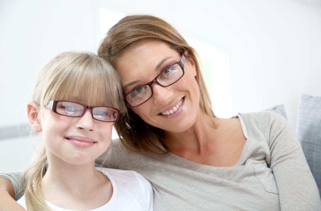 A smiling mother and daughter wearing glasses to correct refractive errors.