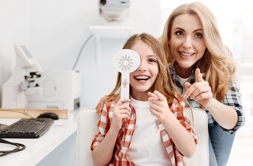 A parent and child pointing to something in front of them while the child is covering one eye with a paddle.