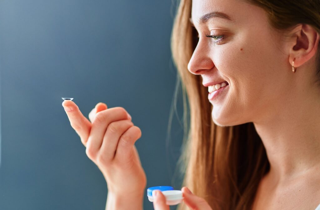 A smiling adult puts their contact lenses in.
