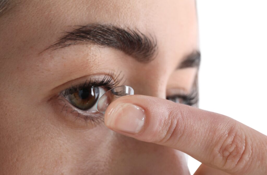 A close up of a person inserting a contact lenses into their eye.