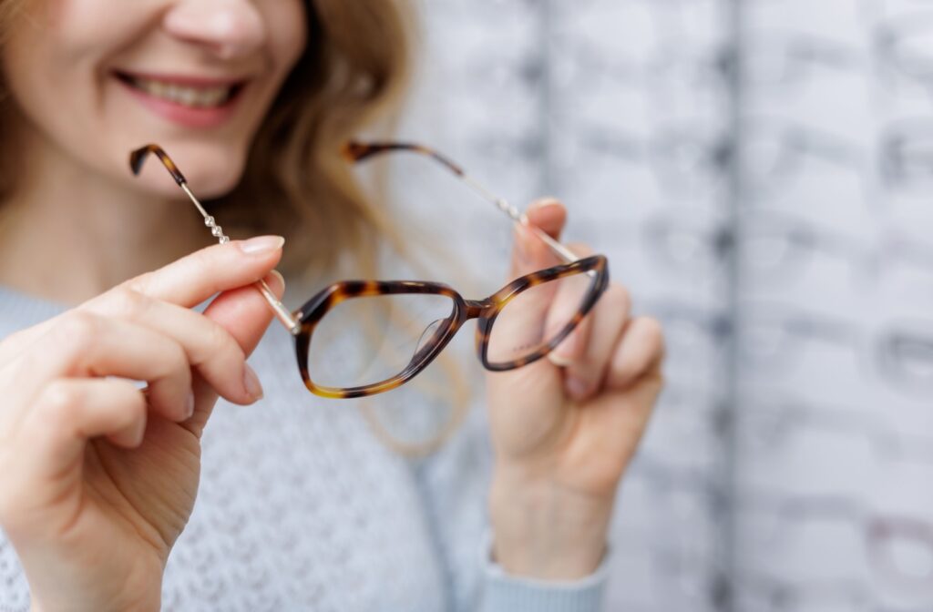 A person holding a pair of glasses to try on and get fitted at their local optometrist's office.