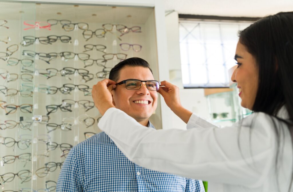 Optician adjusts new eyeglasses on a smiling patient during an eye check-up at a modern optometry clinic.